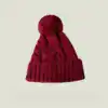 Bonnet cache oreille à pompon rouge bordeaux, tricoté avec motif torsadé et bord côtelé.