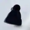 Bonnet cache oreille noir à pompon, style hiver, chaud et élégant.